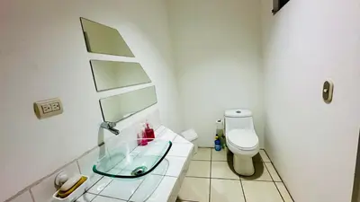 a bathroom with a glass sink and a toilet at SJO Oasis Hostel in San José