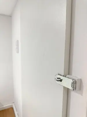 a white door with a metal latch on it at SJO Oasis Hostel in San José