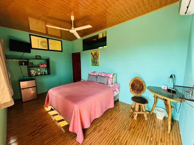 a bedroom with a bed with a pink blanket and a table at Hotel Vista Bonita in Parrita