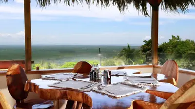a dining room with a table and chairs and a large window at Hotel Vista Bonita in Parrita