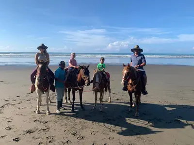 a group of people riding horses on the beach at Hotel Vista Bonita in Parrita