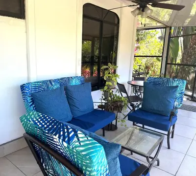 a porch with blue chairs and a glass table at Tropical Oasis in Ojochal in Ojochal