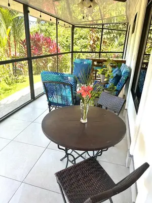a table with chairs and a vase of flowers on a porch at Tropical Oasis in Ojochal in Ojochal
