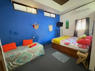a bedroom with two beds and a blue wall at Cheap Hostel Quepos in Quepos