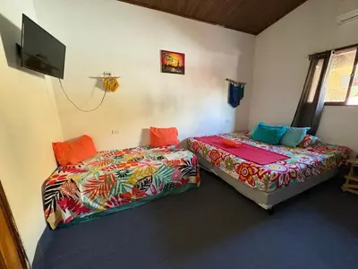 a bedroom with two beds and a flat screen tv at Cheap Hostel Quepos in Quepos