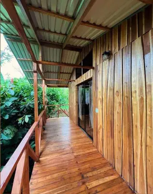 a wooden porch of a wooden house with a roof at Río Celeste, Cacahua Lodge in Rio Celeste
