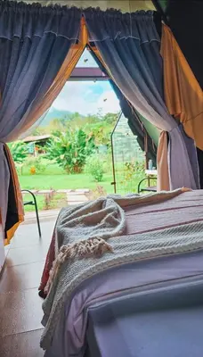 a bed in a room with a large window at Flora Glamping de Abuela in Fortuna