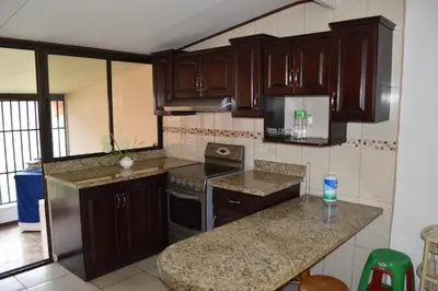 a kitchen with wooden cabinets and a counter top at SERENITY HOME H Y M in Turrialba