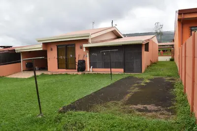 a house with a grass yard in front of it at SERENITY HOME H Y M in Turrialba