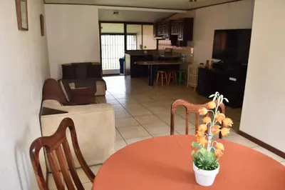 a room with a table and chairs and a living room at SERENITY HOME H Y M in Turrialba