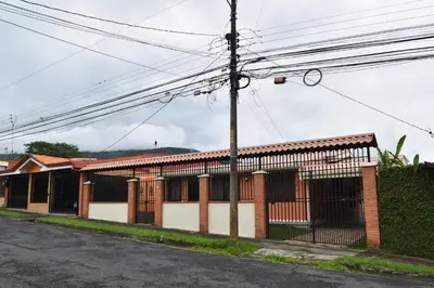 a brick building with a fence on the side of a street at SERENITY HOME H Y M in Turrialba