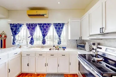 a kitchen with white cabinets and blue curtains at La Cometa 16 in Tamarindo