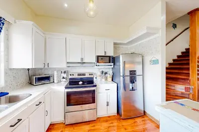 a kitchen with white cabinets and a stainless steel refrigerator at La Cometa 16 in Tamarindo