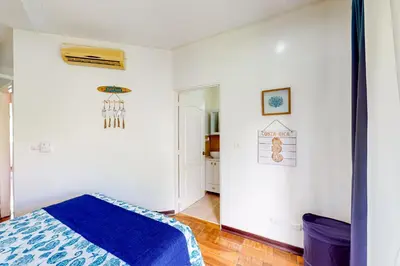 a bedroom with white walls and a blue blanket on a bed at La Cometa 16 in Tamarindo