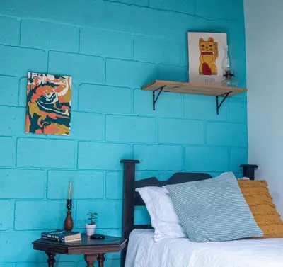 a bedroom with a blue brick wall and a bed at Lolas Hostal Hab Individual 2 Baño Compartido in San José