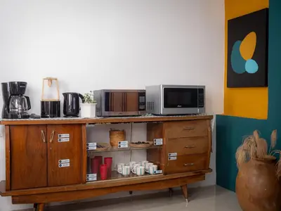 a wooden cabinet with a microwave and a coffee maker at Lolas Hostal Hab. doble (baño privado) in San José