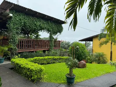 a garden with a bench in front of a house at Hotel Aurora Inn, Nuevo Arenal in Nuevo Arenal