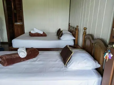 three beds in a room with white sheets and pillows at Hotel Aurora Inn, Nuevo Arenal in Nuevo Arenal