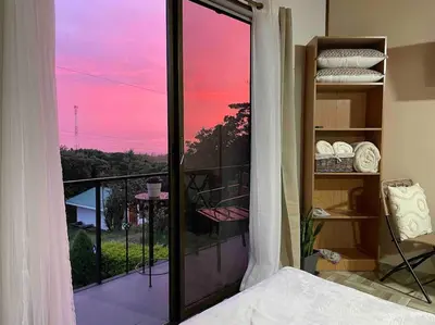 a bedroom with a balcony with a view of a sunset at Alma Verde 2 in Monteverde Costa Rica