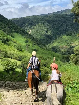 a man and a woman riding horses down a hill at Casa Pitahaya in Monteverde Costa Rica