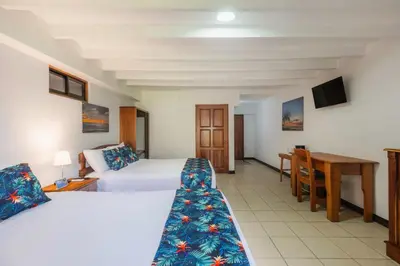 a hotel room with two beds and a desk at Jaco Laguna Resort & Beach Club in Jacó