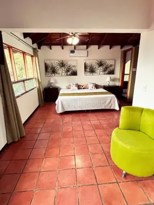 a bedroom with a bed and a green chair at Siwõ Art Guesthouse in Ocotal