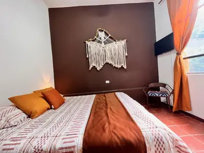 a bedroom with a bed and a wall with a window at Siwõ Art Guesthouse in Ocotal