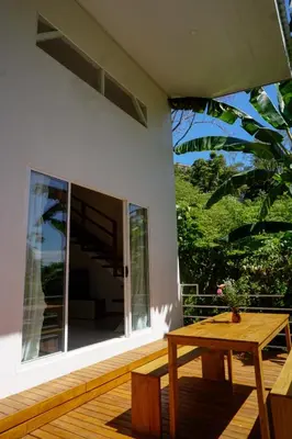 a patio with a wooden table and a large window at Villa SOL in Santa Teresa Beach