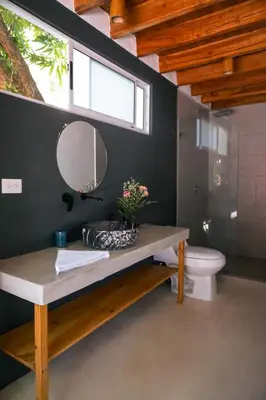 a bathroom with a sink and a mirror and a toilet at Villa SOL in Santa Teresa Beach