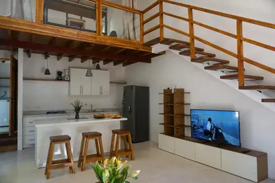 a kitchen with a kitchen island with a tv and stairs at Villa SOL in Santa Teresa Beach