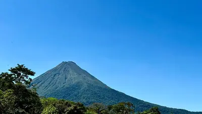 a mountain with trees in front of a blue sky at Arenal Monara in Fortuna