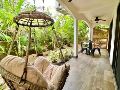 a porch with a swinging chair and a table at Quepos Fishing Villa in Quepos