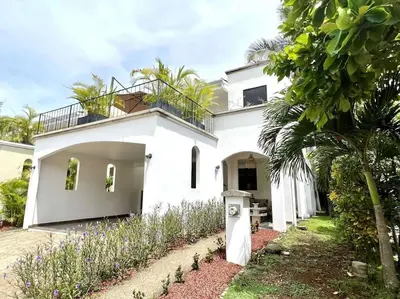 a white house with a palm tree in front of it at Quepos Fishing Villa in Quepos