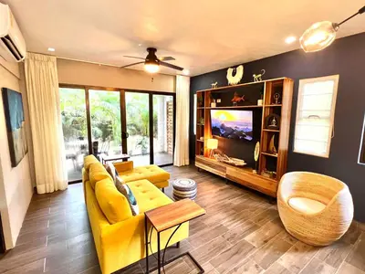 a living room with a yellow couch and a tv at Quepos Fishing Villa in Quepos