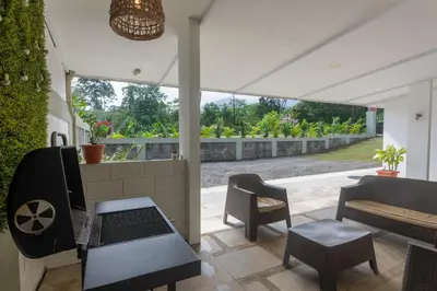 a patio with a bench and chairs and a table at Arenal White Bliss Villa in Fortuna