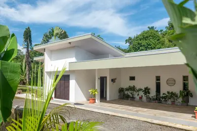 a white house with plants in front of it at Arenal White Bliss Villa in Fortuna
