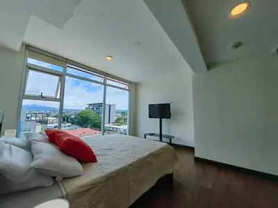 a bedroom with a bed and a large window at 706 Torres Los Yoses Hermoso apartamento en Barrio Escalante con Parqueo in San José