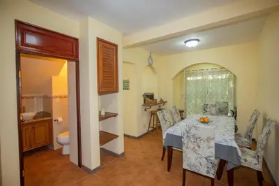 a dining room with a table and a bathroom at Three Bedroom Sunny Townhome in Coco