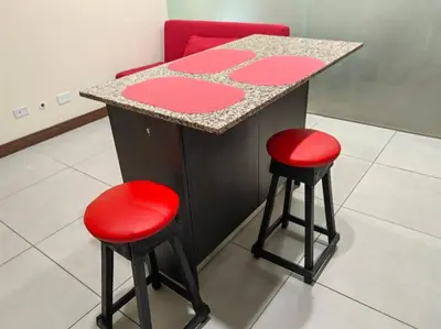 a counter with two red stools next to a counter top at 1001 Torres Los Yoses Apartamento con A/C y parqueo full equipado in San José