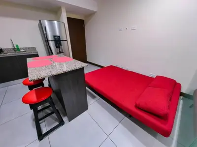 a red couch sitting next to a counter in a kitchen at 1001 Torres Los Yoses Apartamento con A/C y parqueo full equipado in San José