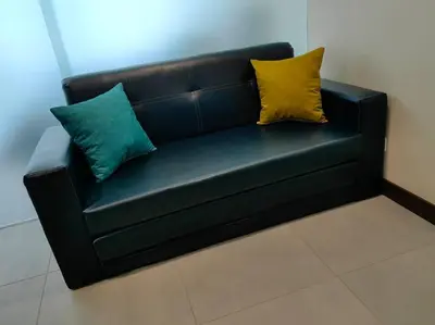 a black leather couch with three pillows on it at 1505 Torre los Yoses Hermoso Apartamento en Barrio Escalante con Parqueo in San José