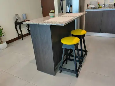 a kitchen with a counter with two yellow bar stools at 1505 Torre los Yoses Hermoso Apartamento en Barrio Escalante con Parqueo in San José
