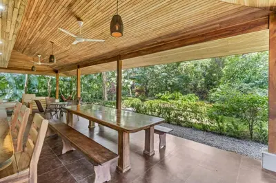 a dining room with a wooden table and benches at Stylish 3-Bedroom Tropical Escape with Pool & Outdoor Living, 1 Block from Playa Potrero in Potrero