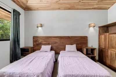 two beds sitting in a room with a window at Stylish 3-Bedroom Tropical Escape with Pool & Outdoor Living, 1 Block from Playa Potrero in Potrero