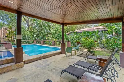an outdoor patio with a swimming pool and chairs at Stylish 3-Bedroom Tropical Escape with Pool & Outdoor Living, 1 Block from Playa Potrero in Potrero