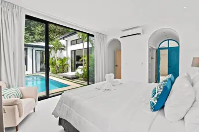 a white bedroom with a large bed and a pool at Modern Garden Villa with Private Pool, Outdoor Kitchen & Separate Casita Near Playa Potrero in Potrero