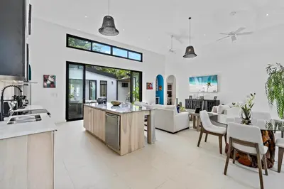 an open kitchen and living room with white furniture at Modern Garden Villa with Private Pool, Outdoor Kitchen & Separate Casita Near Playa Potrero in Potrero