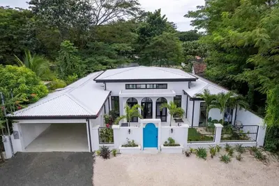 a white house with a blue door at Modern Garden Villa with Private Pool, Outdoor Kitchen & Separate Casita Near Playa Potrero in Potrero