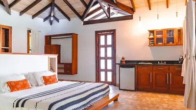 a bedroom with a large bed and a kitchen at Playa Cielo Beachfront Hotel - Santa Teresa, Costa Rica in Santa Teresa Beach