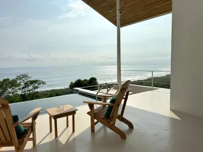 a balcony with chairs and a table and a view of the ocean at Les Roches - Paradise Retreat in Santa Teresa Beach
